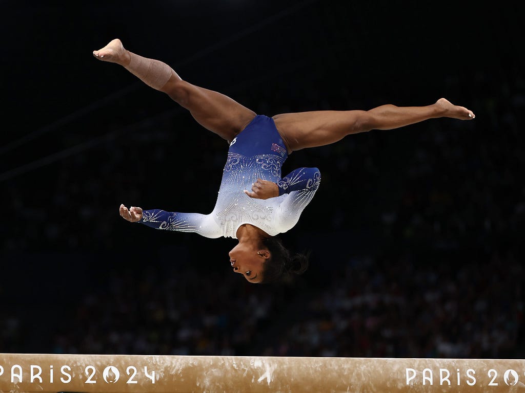 Simone Biles flips on a balance beam at the Paris Olympics in 2024