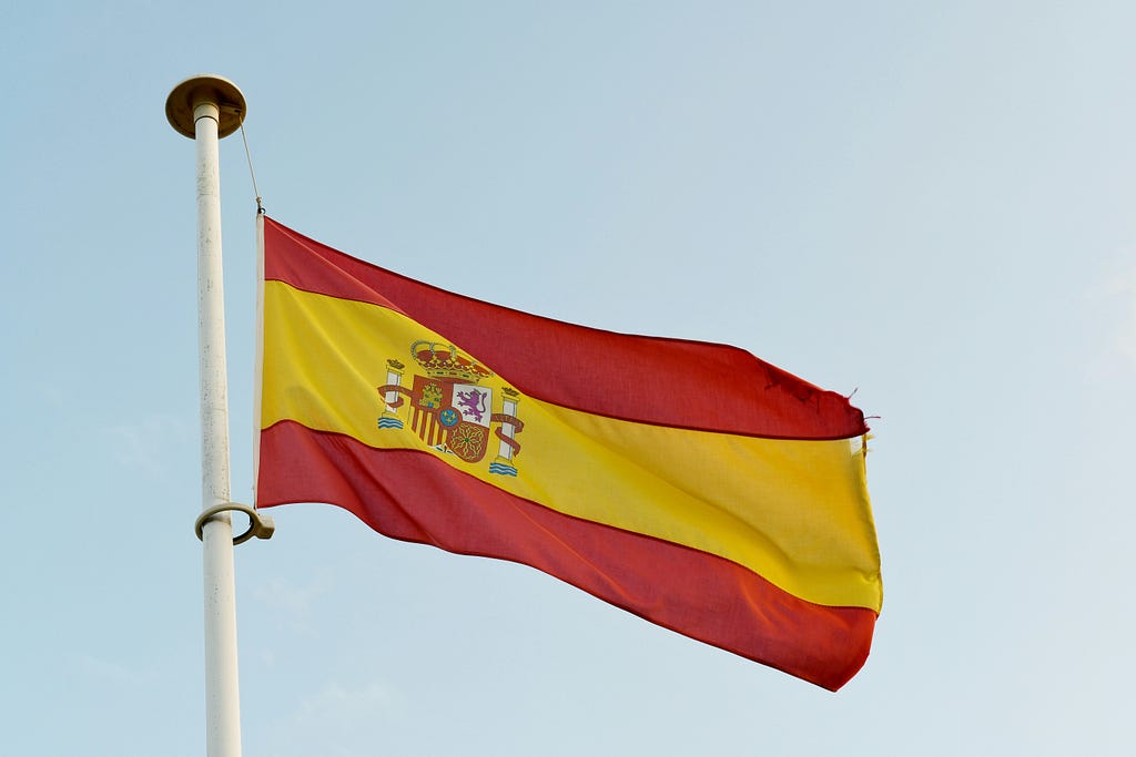Spain’s flag fluttering on a bright sky background.