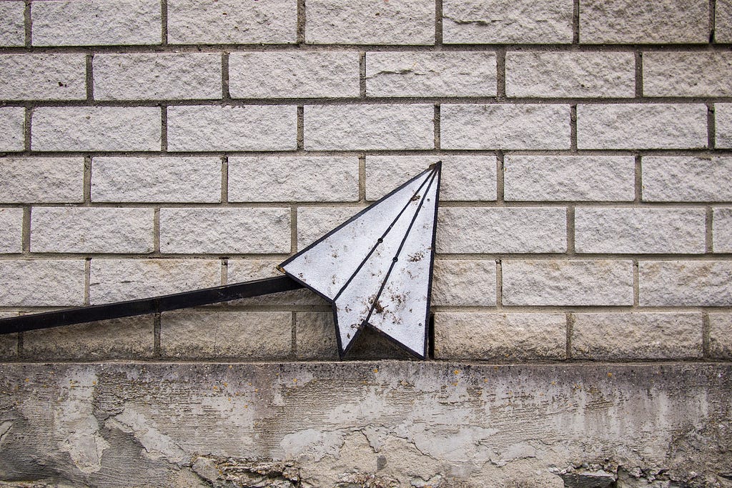 a photo of an airplane symbol resting against a brick wall indicating ‘send’