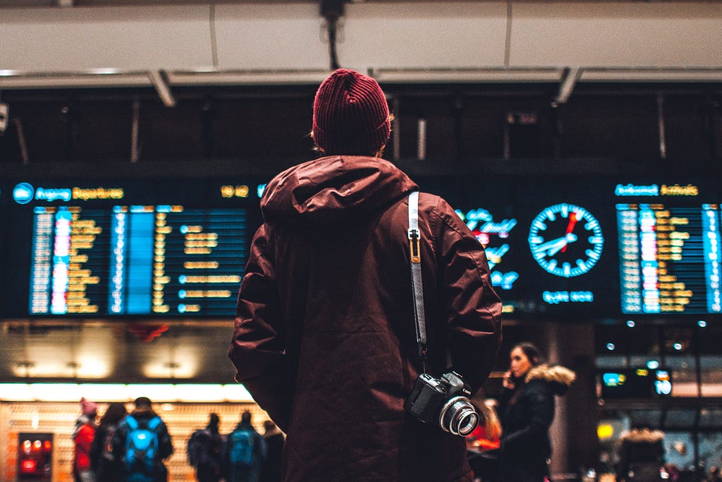 A passenger is looking at flight schedule board at Oslo airport terminal in Norway.