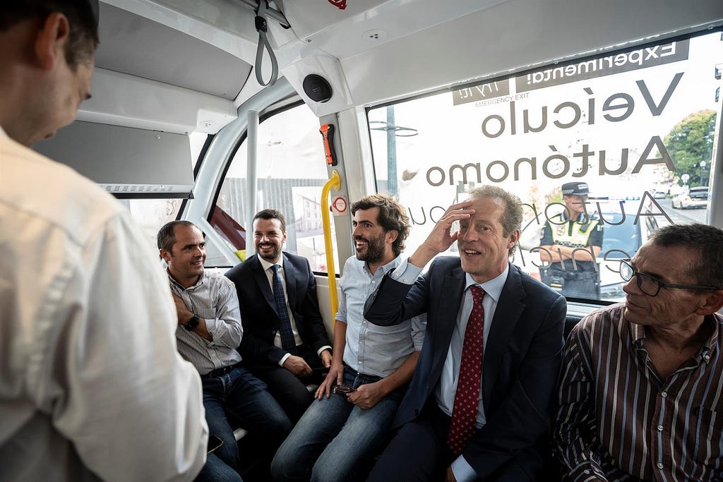 Photograph of the interior of an autonomous shuttle driving in Aveiro, where multiple people are smiling and talking about the experience (taken in October 2022)