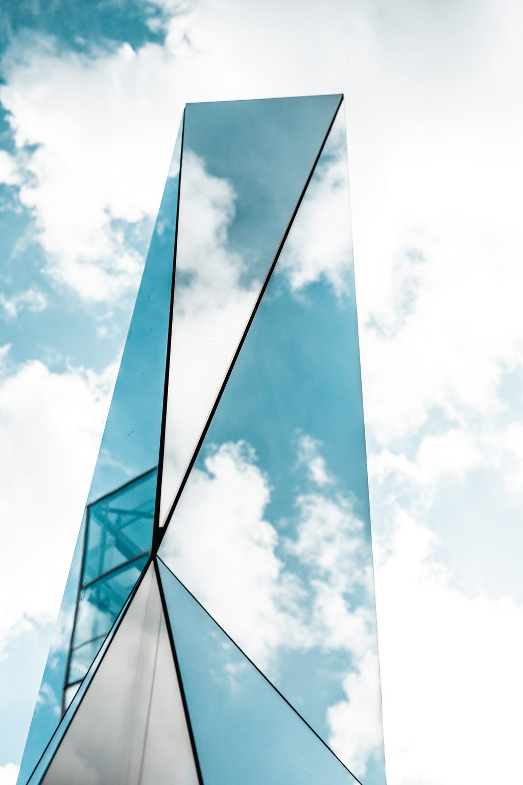 Sculpture made of mirrors reflecting a blue, cloudy sky