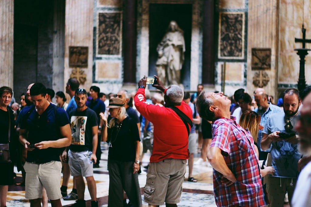 A group of people in an art gallery looking up and taking pictures