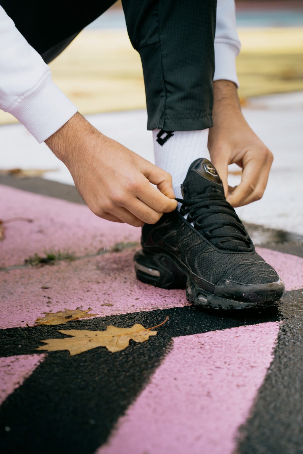 Closeup of a man tying shoelaces of a black sneaker.