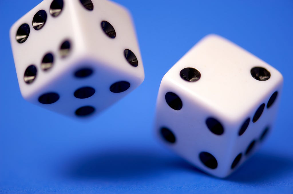 A standard set of dice midroll against a blue background.