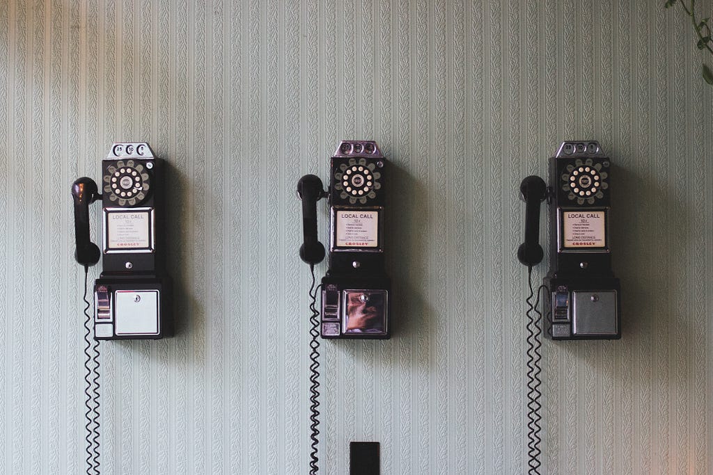 Three payphones hanging from the wall.