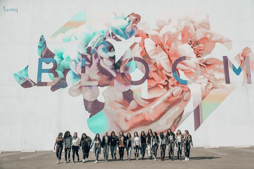 A group of women stand before a wall mural