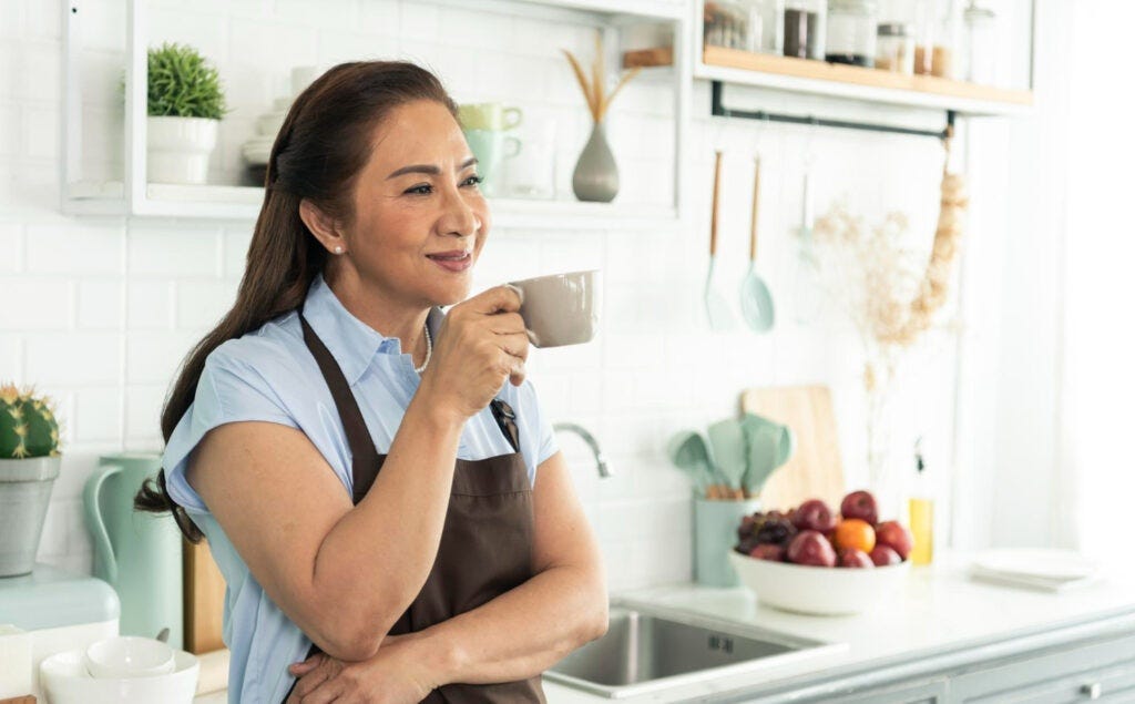 relax-asian-older-woman-apron-holding-cup-coffee-kitchen-room — If you’re a woman over 50, it’s often difficult to know which diet is best, especially as you’re experiencing physical changes associated with aging — Rumbomag