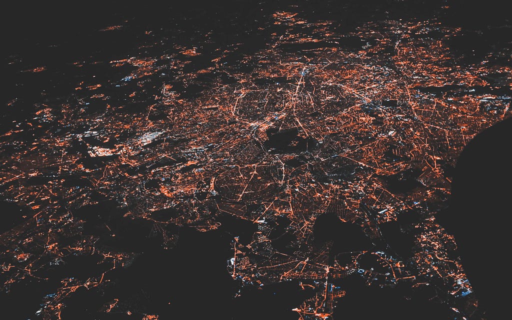 nighttime aerial photo of a city, streetlights and roads visible.