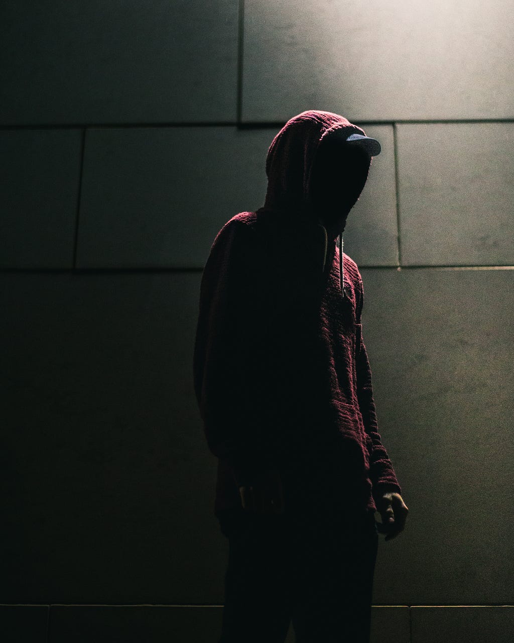 Hooded figure in a dark alleway.
