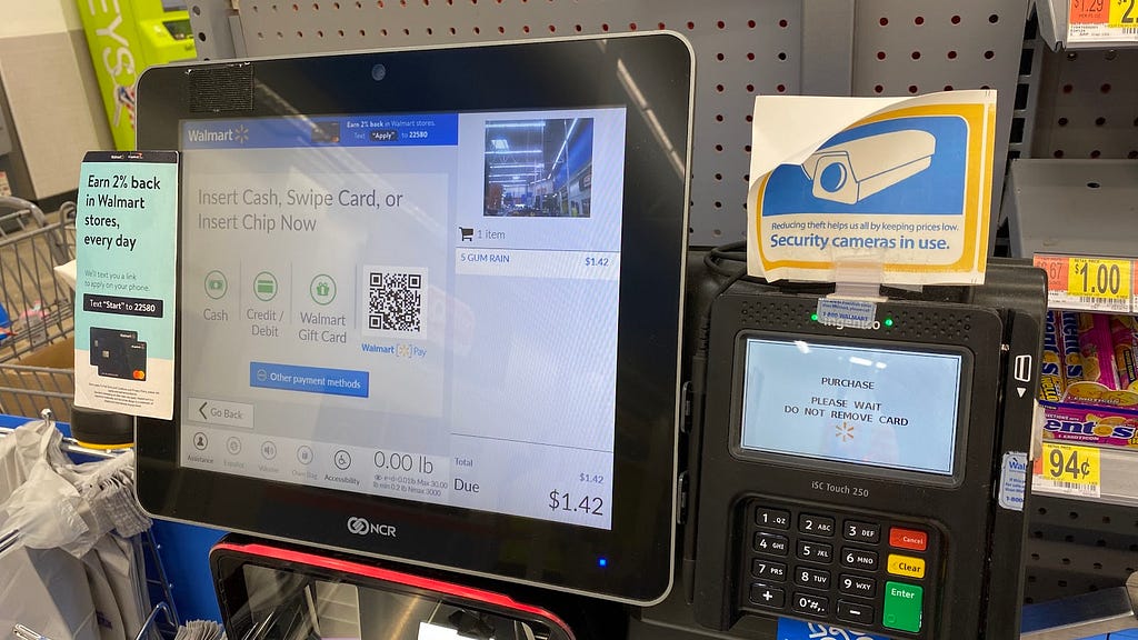 Self checkout machine from Walmart that instructs the user to wait while the payment is processing.