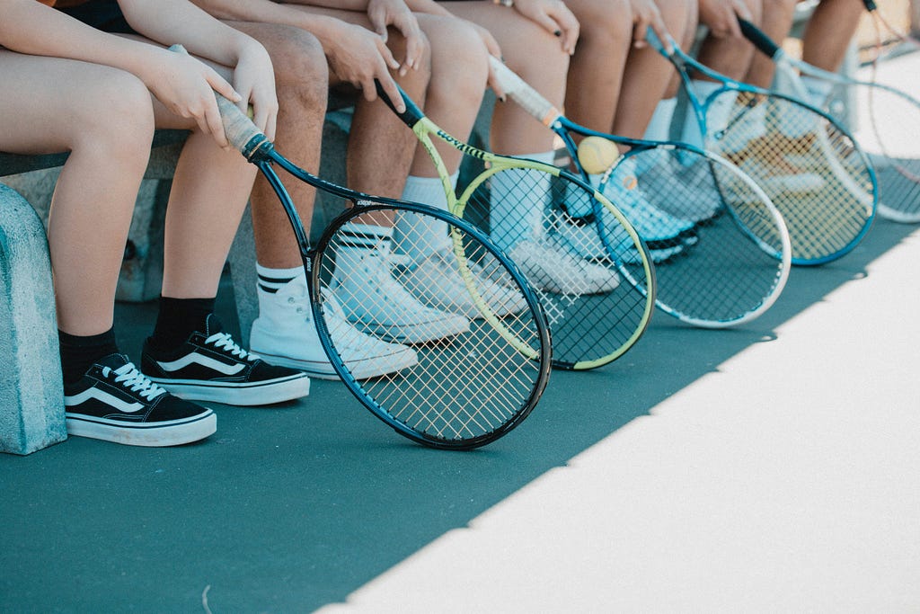 6 tennis rackets and legs of 6 people