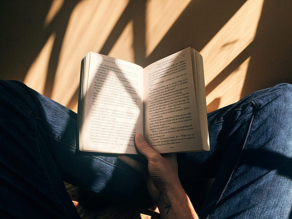 Reading a book sitting cross-legged on the floor