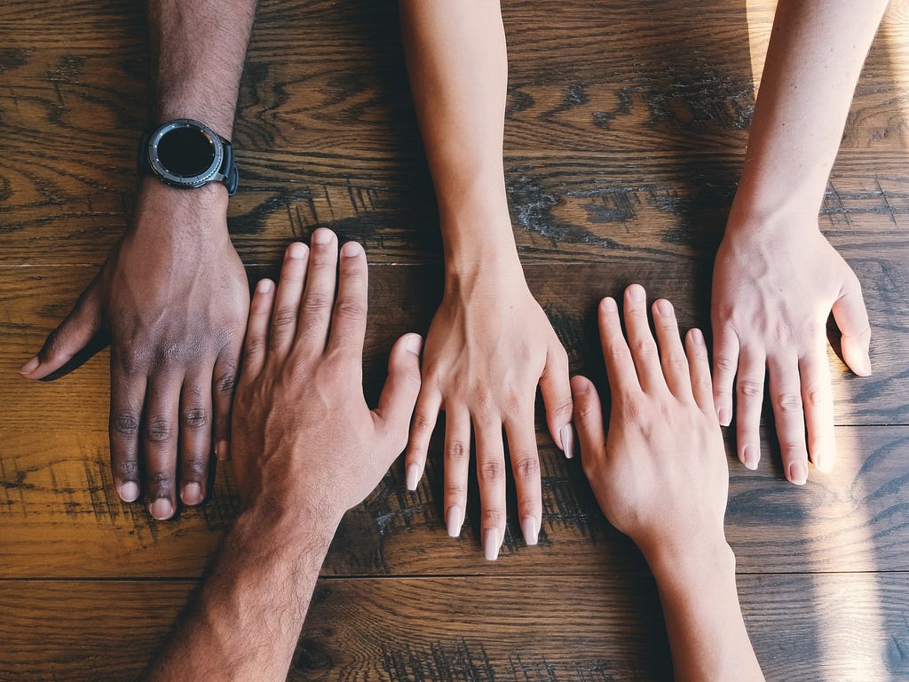 Five hands on a wooden table