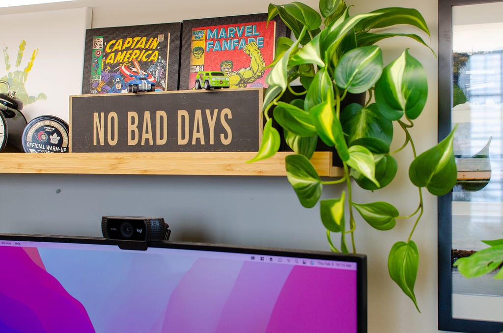 Espaço de trabalho contendo plantas e uma placa decorativa escrito "No bad days".