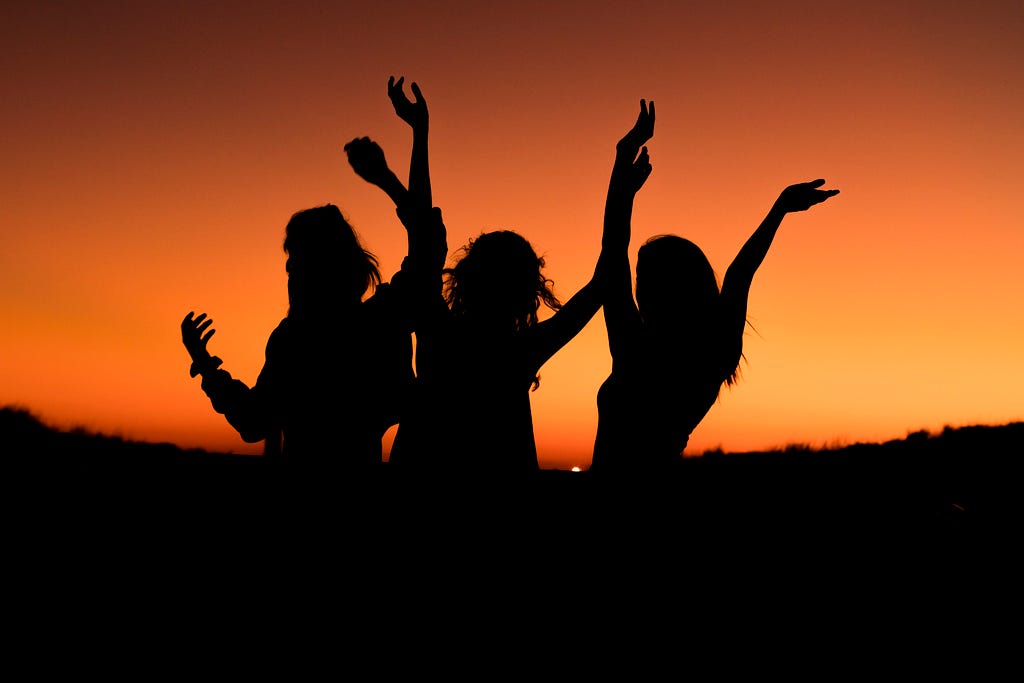 a silhouette of three women celebrating life