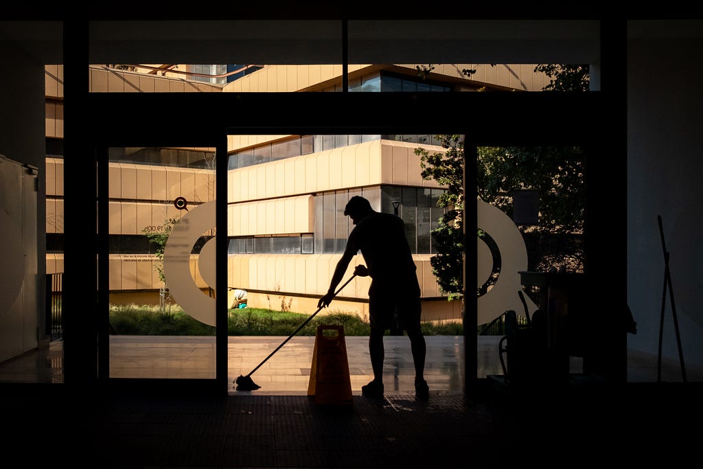 Silhouette of a man mopping in front of automatic doors