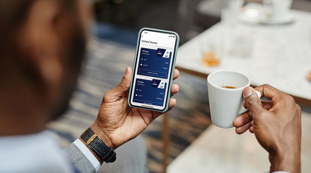 Businessman holding a smartphone with the airalo app and an espresso