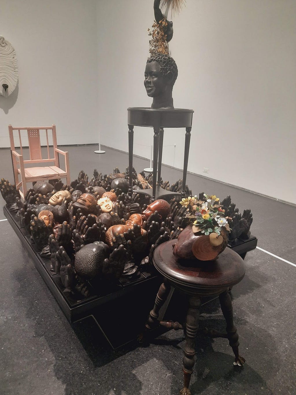 Image of Nick Cave sculpture featuring various wooden faces and hands
