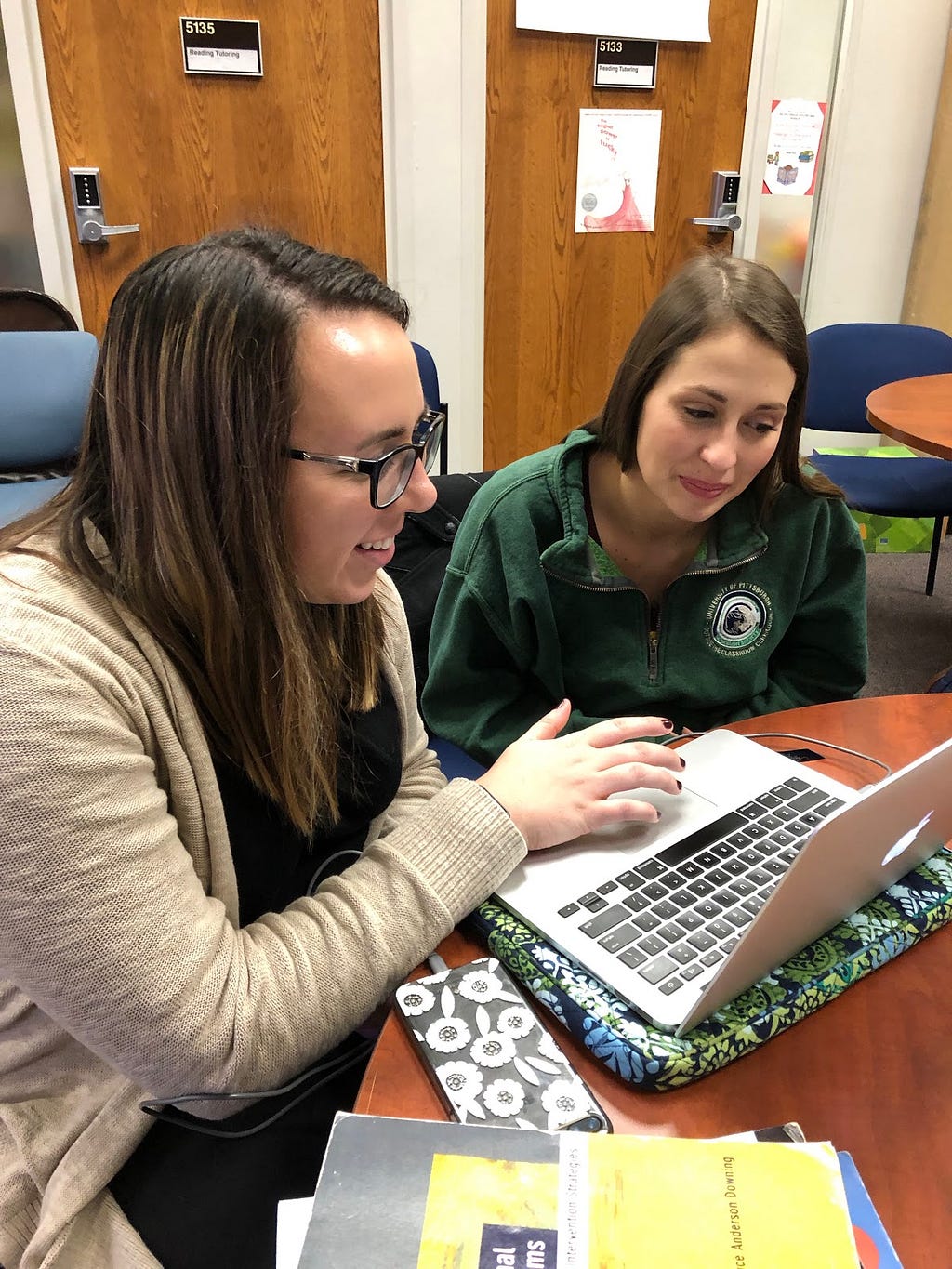 Two education students look at a laptop while doing the Teacher Moments application based simulation.