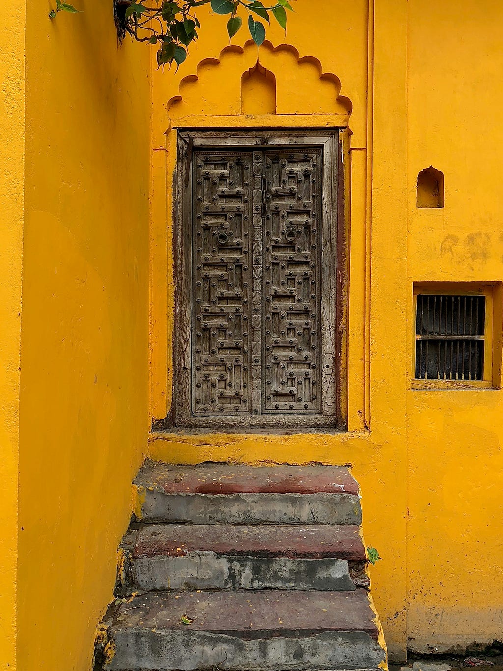 A closed wooden door against a yellow wall.