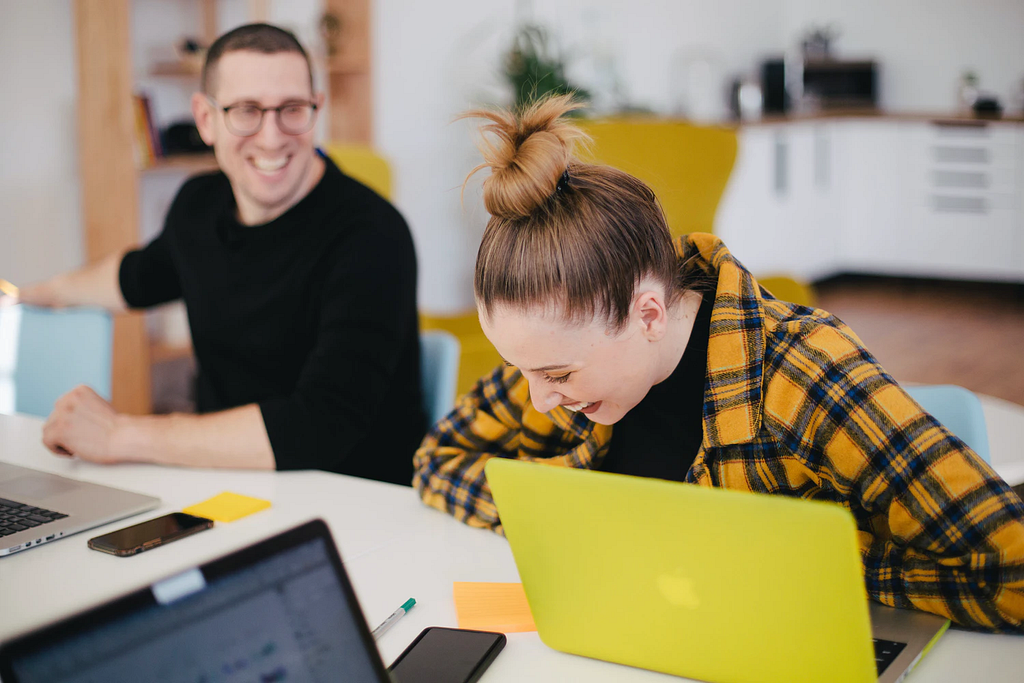 Man and woman sitting and laughing at a desk