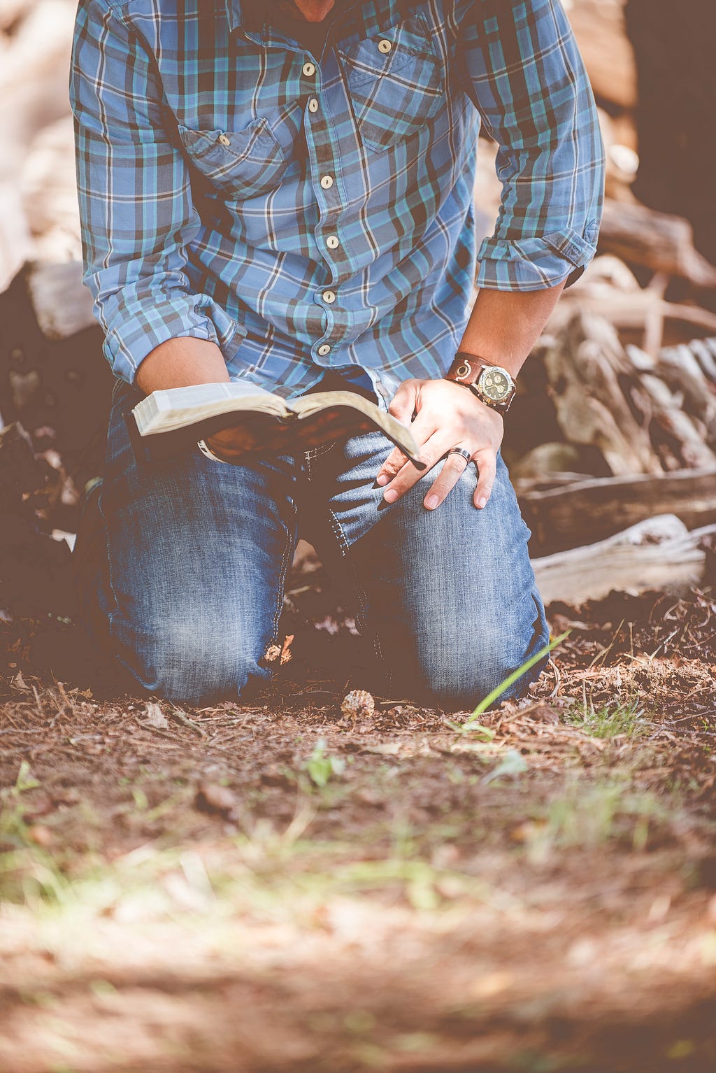 a young man kneeling down with bible in his hands