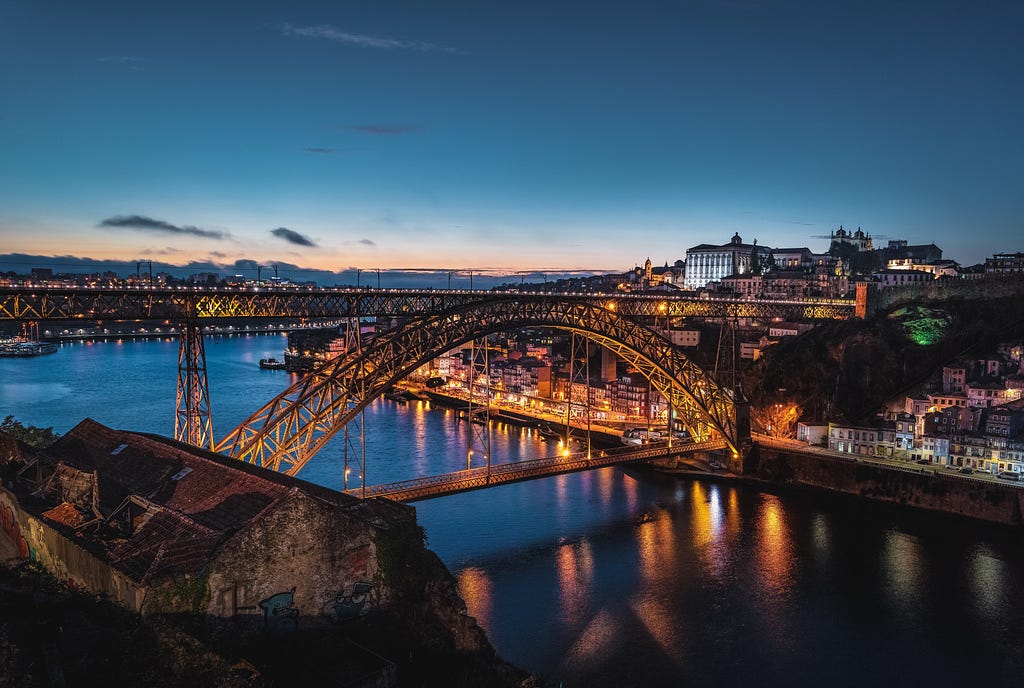 The image shows Dom Luís I Bridge, a double-deck metal arch bridge that spans the River Douro between Oporto and Vila Nova de Gaia in Northern Portugal.