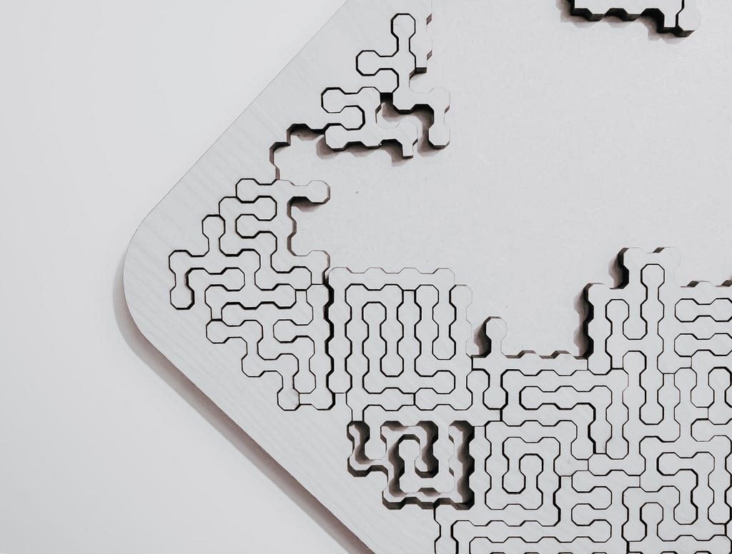 An unusual white puzzle on a white background, with squiggly white-colored puzzle pieces shaped like nodes. The puzzle is less than halfway completed, showing the white table beneath it.