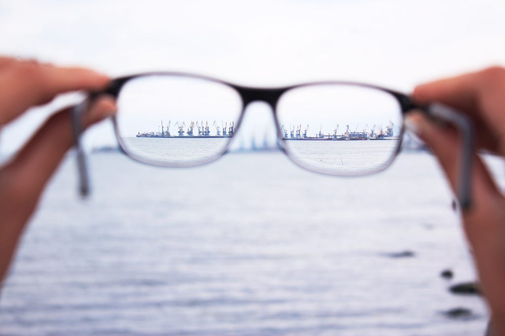 Image of a person holding glasses that shows a clear vision.