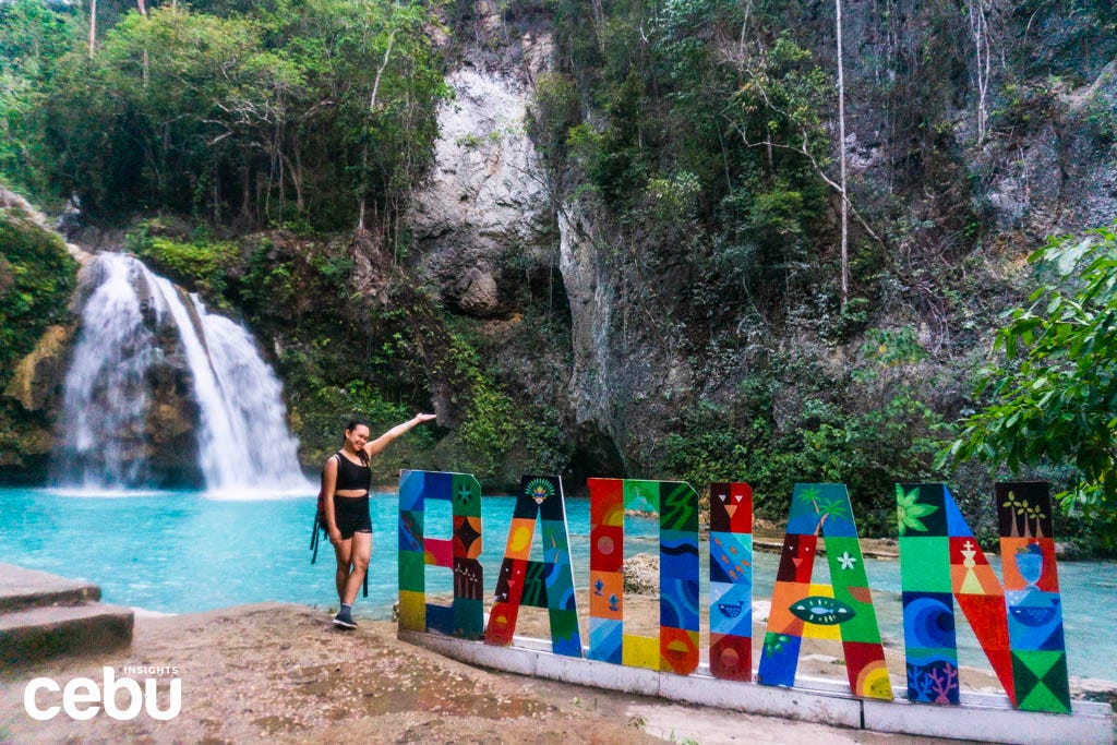 Woman poses at Badian sign at Kawasan Falls