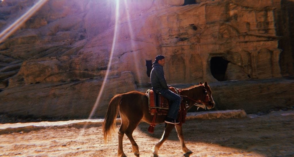 Digital nomad sitting on horse in front of lost city of Petra