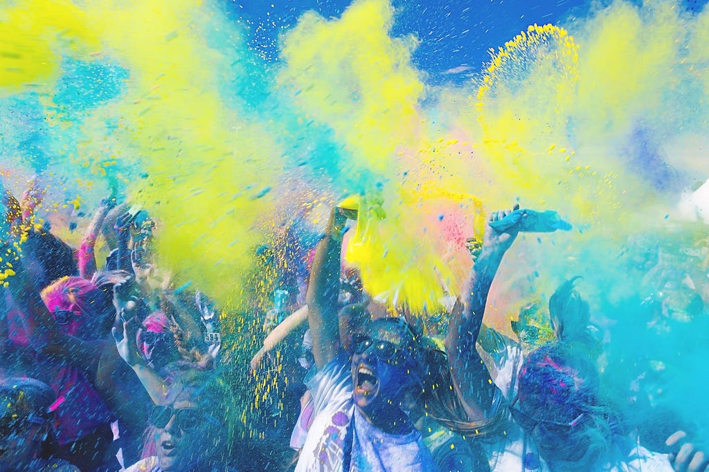 Picture of people partying at a paint festival with brightly coloured paints flung through the air