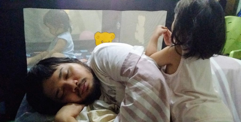 Parent sleeping on the floor as toddler plays on top of him