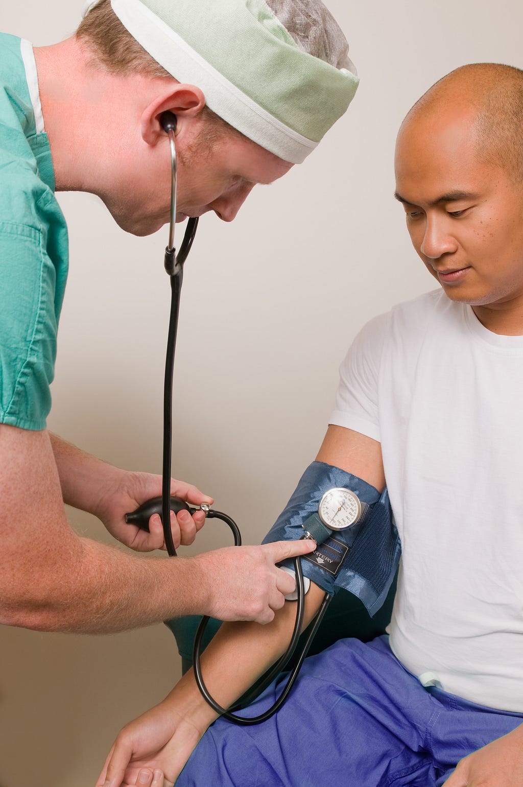 A white male checking an Asian’s blood pressure