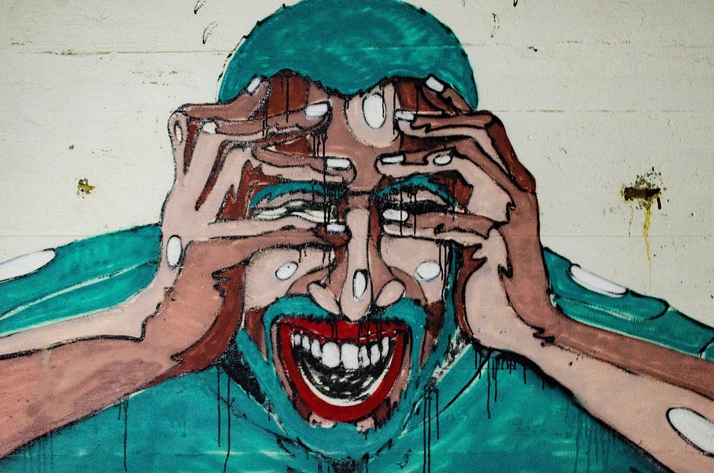 Graffiti art of a man holding his head and screaming with paint drips