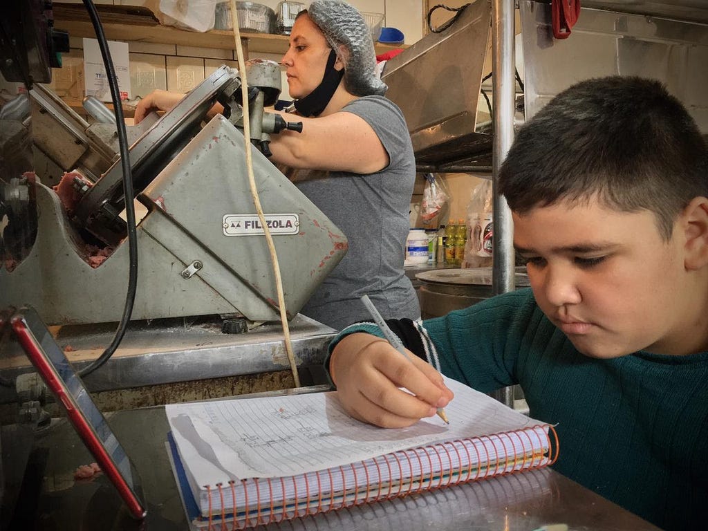 João, aluno do 5º ano, fazendo as lições da escola no trabalho de sua mãe. / Imagem: Bruna Breyer