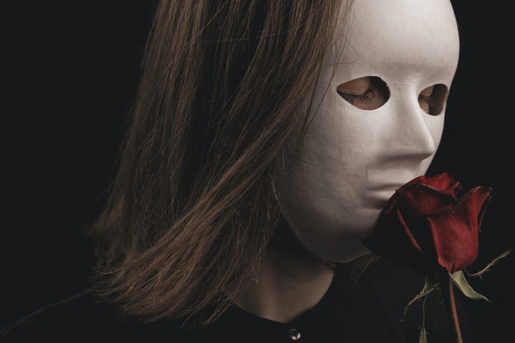 A woman with a white mask on smelling the essence of a rose flower