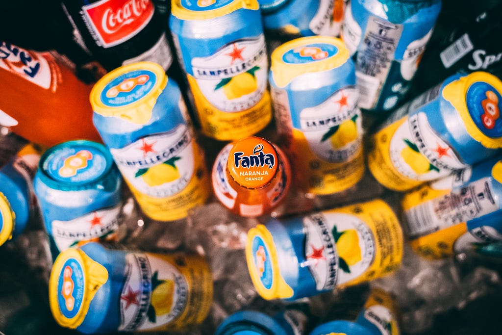 Fanta bottle surrounded by many cans.