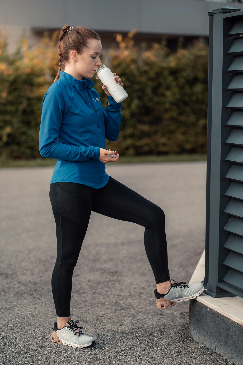 Woman out jogging stopped to sip from her water bottle