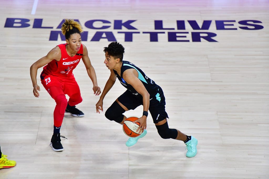 Layshia Clarendon dribbles past “Black Lives Matter” printed on the WNBA hardwood.