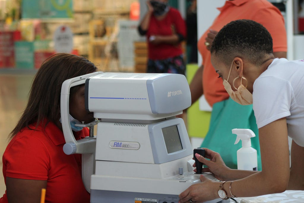 a woman taking a free eye test to shoppers at Maponya Mall in Soweto while raising awareness about the #myschool #myvillage