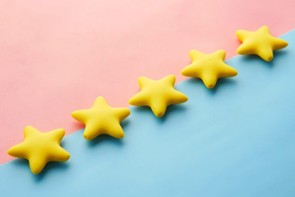 five star crackers lined up in a diagonal row; one side is baby pink and the other side is baby blue. The crackers themselves are yellow