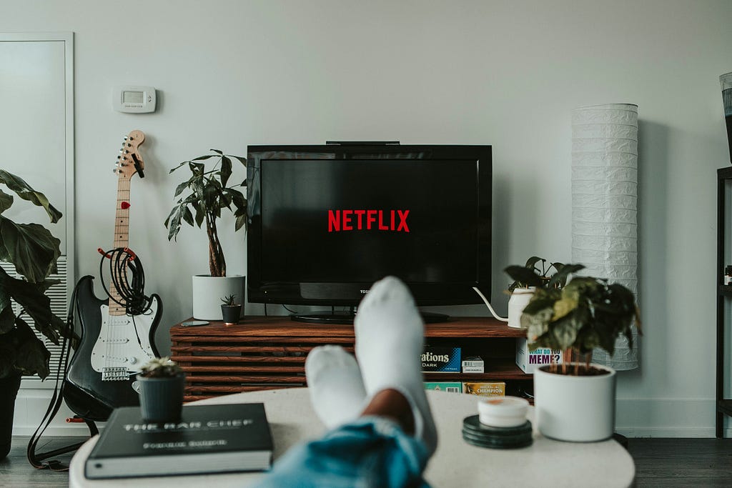 Person viewing streaming service interface with AI-driven recommendations on TV screen.