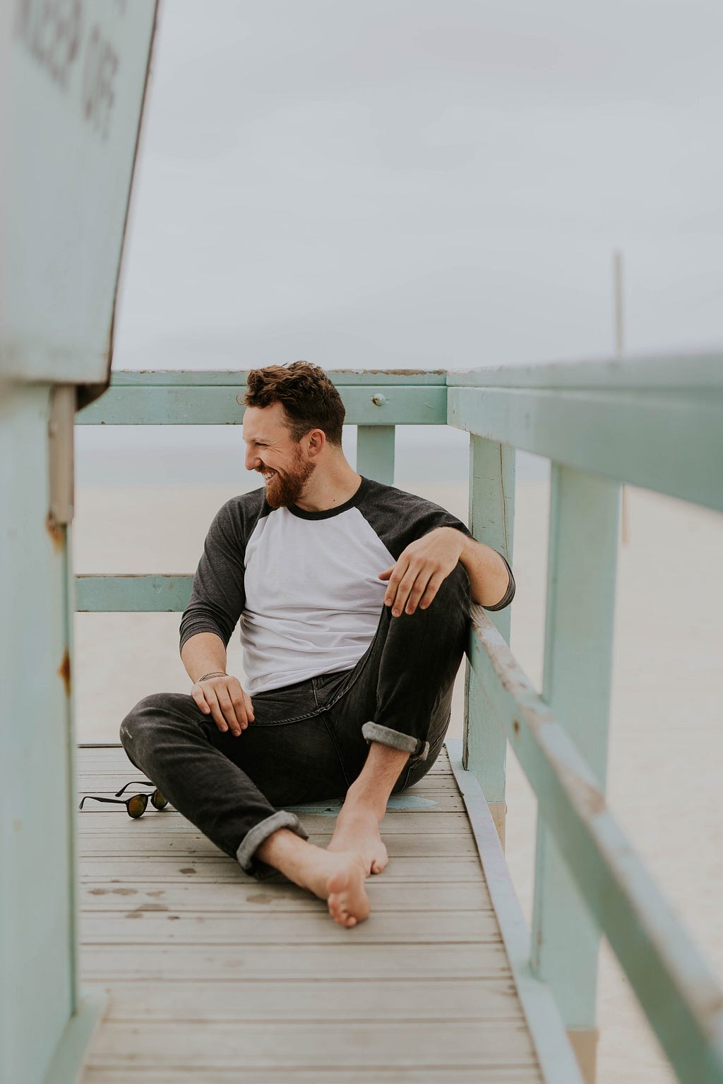 A happy and healthy man on the beach, sitting on the lifeguard’s floor