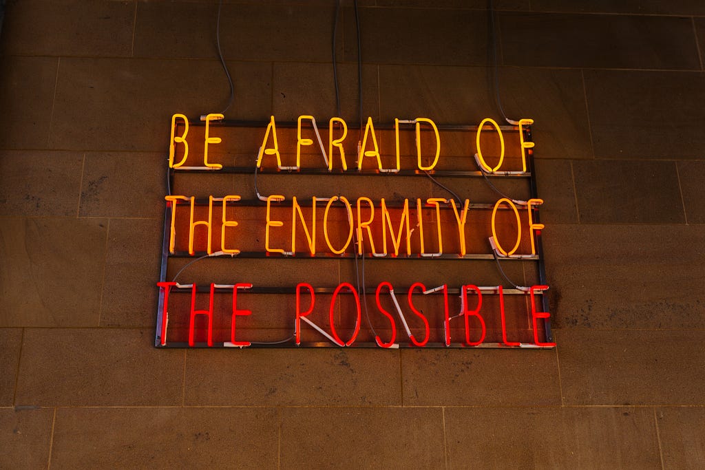 A retro sign on a wall reads — Be afraid of the enormity of the possible