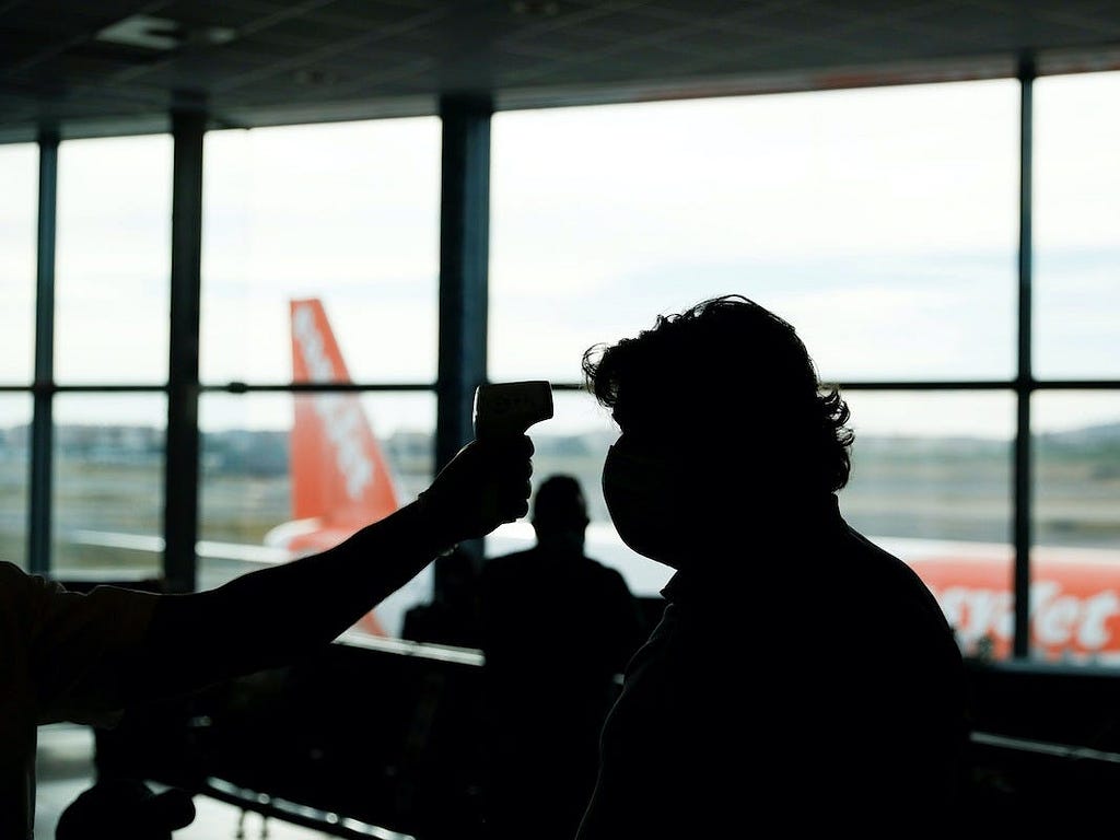 A passenger gets their temperature taken at the airport.