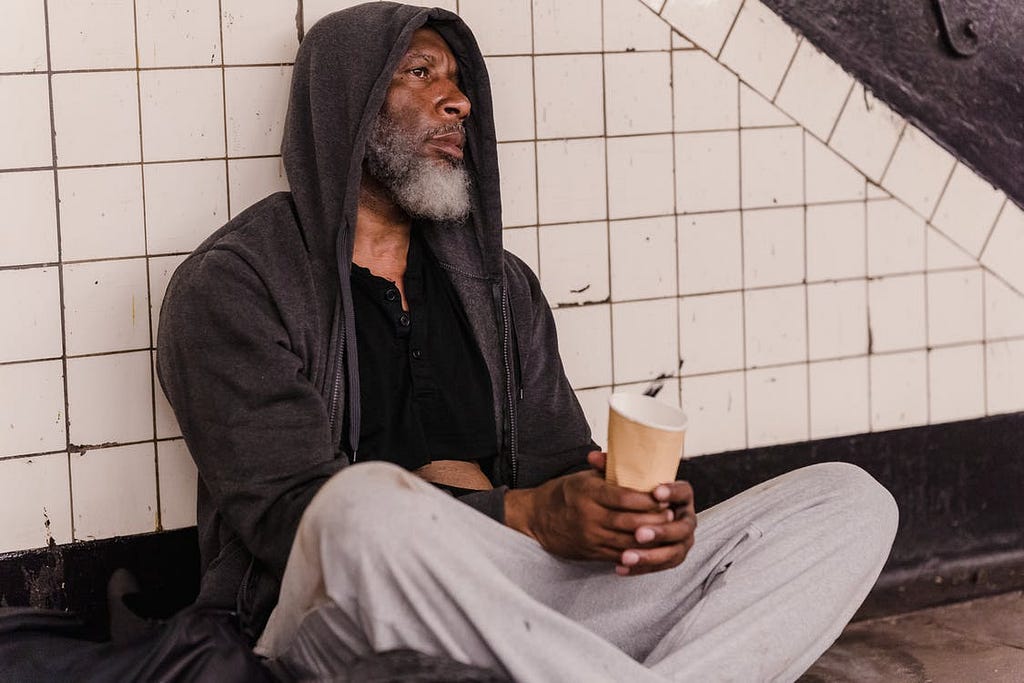 A beggar sitting in a railway station waiting for people to help him.