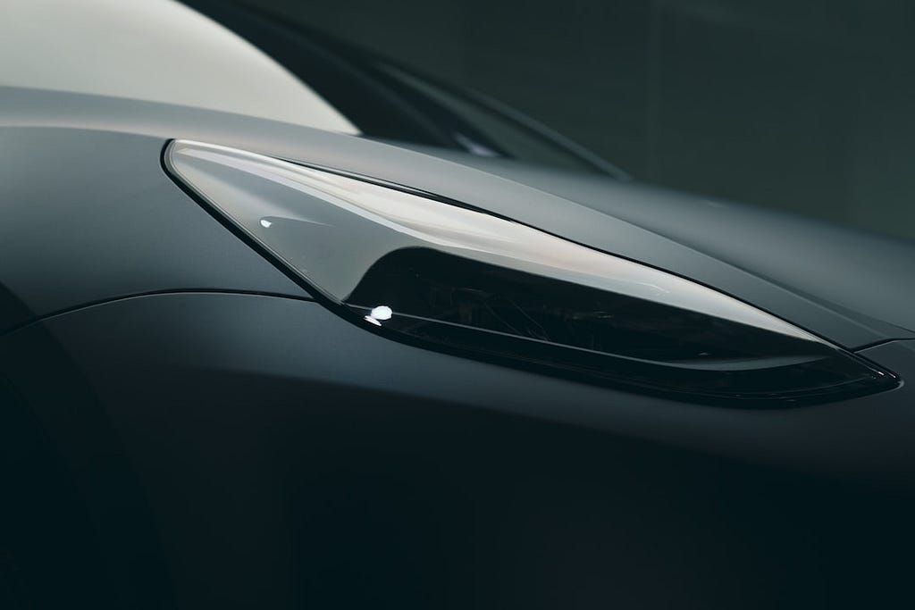 An up-close shot of the headlight of a black Model 3 or Model Y.