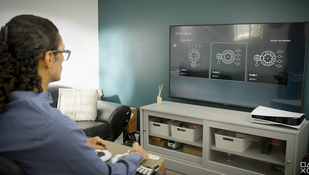 這是使用PS5無障礙操作的示意圖，玩家正看著電視螢幕，雙手則正在操作無障礙控制器